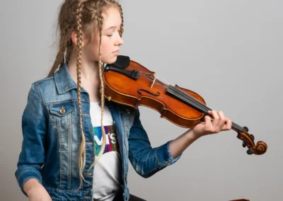 A portrait of a young girl holding gracefully her violin and bow