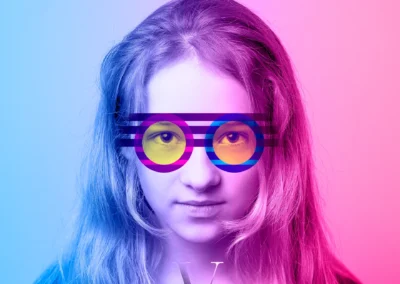 A portrait of a young girl looking straight into the camera wearing funky blue and pink striped vector drawn glasses
